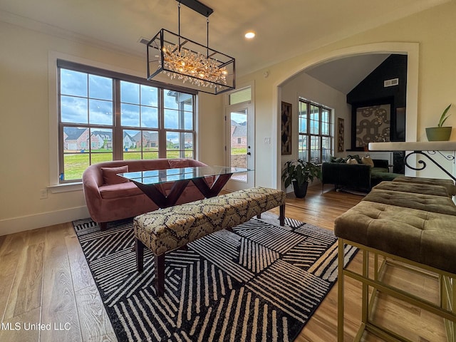 living area featuring healthy amount of natural light, arched walkways, wood finished floors, crown molding, and recessed lighting