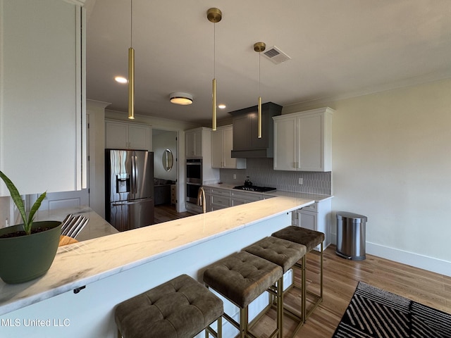 kitchen with stainless steel appliances, decorative backsplash, baseboards, a kitchen bar, and wood finished floors