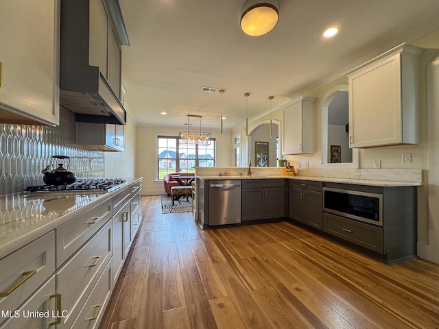 kitchen with appliances with stainless steel finishes, wood finished floors, light countertops, recessed lighting, and hanging light fixtures