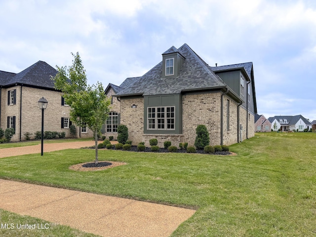 view of front of property with a front lawn, brick siding, and roof with shingles