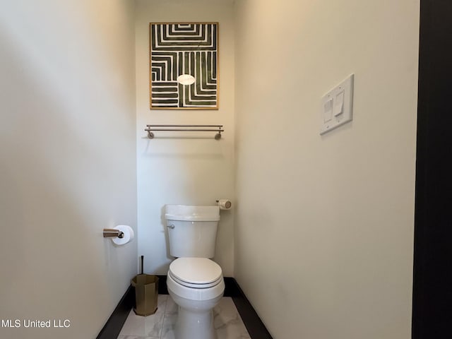 bathroom with marble look tile flooring, toilet, and baseboards