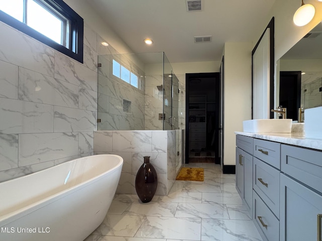 bathroom featuring a stall shower, vanity, a freestanding tub, marble finish floors, and recessed lighting
