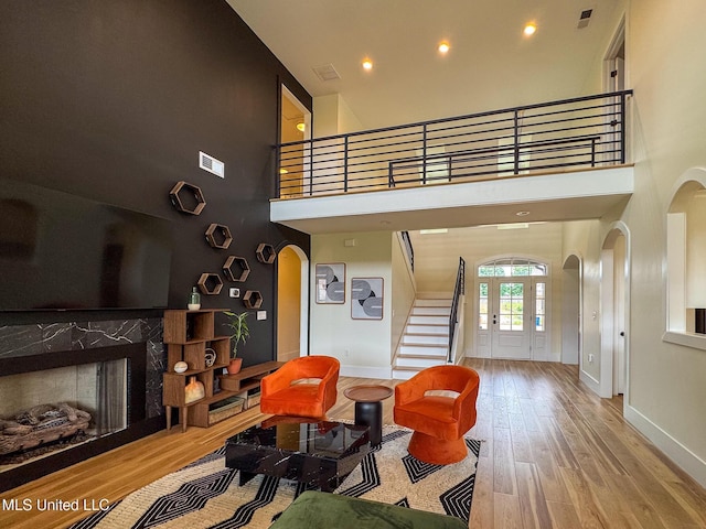 living room with arched walkways, a high ceiling, baseboards, stairway, and recessed lighting