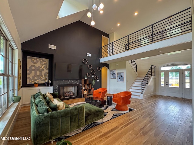 living room featuring high vaulted ceiling, stairway, wood finished floors, a high end fireplace, and baseboards