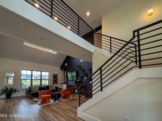 staircase featuring high vaulted ceiling and wood finished floors
