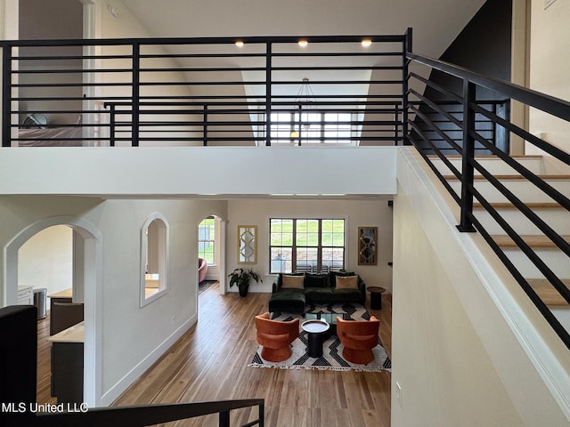 living area featuring wood finished floors, baseboards, stairway, and arched walkways