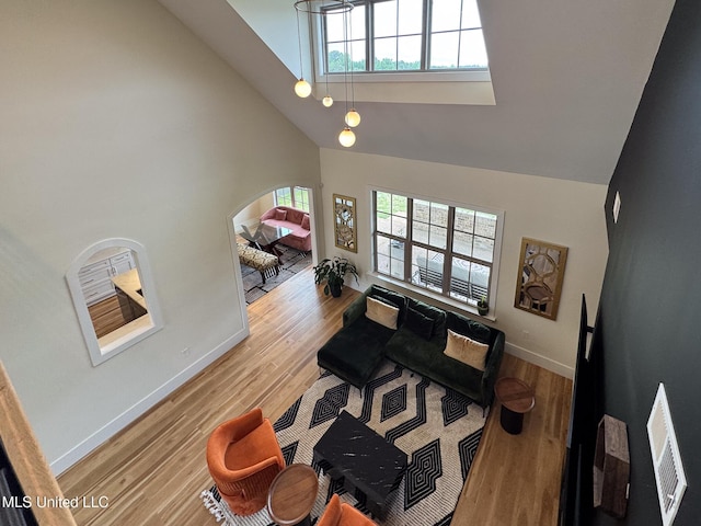 living room featuring high vaulted ceiling, baseboards, and wood finished floors