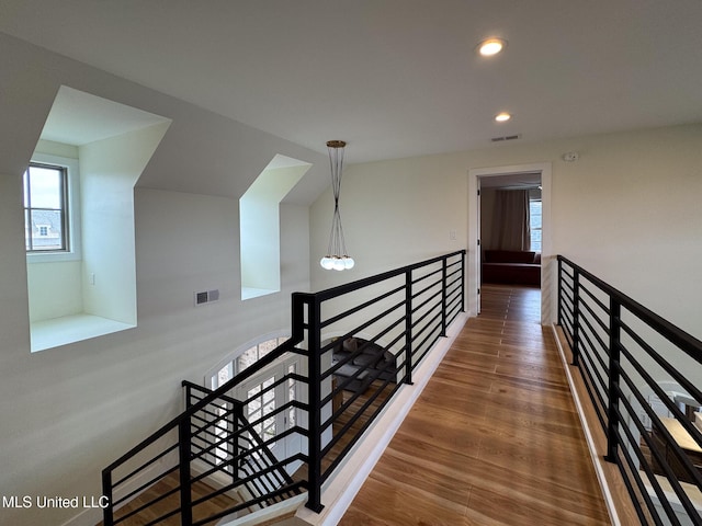 stairs with plenty of natural light, recessed lighting, and wood finished floors