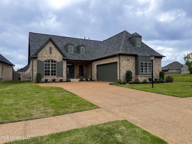 french country inspired facade with brick siding, a garage, driveway, and roof with shingles