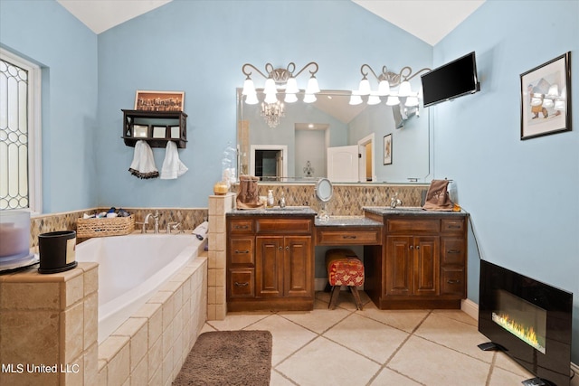 bathroom featuring vanity, lofted ceiling, tiled tub, and tile patterned floors