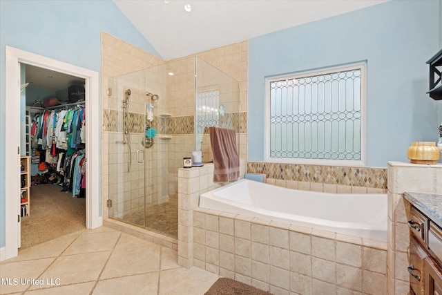 bathroom featuring vanity, vaulted ceiling, shower with separate bathtub, and tile patterned floors