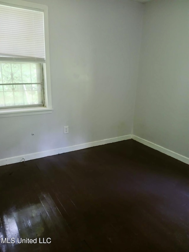 unfurnished room featuring baseboards and dark wood-style flooring