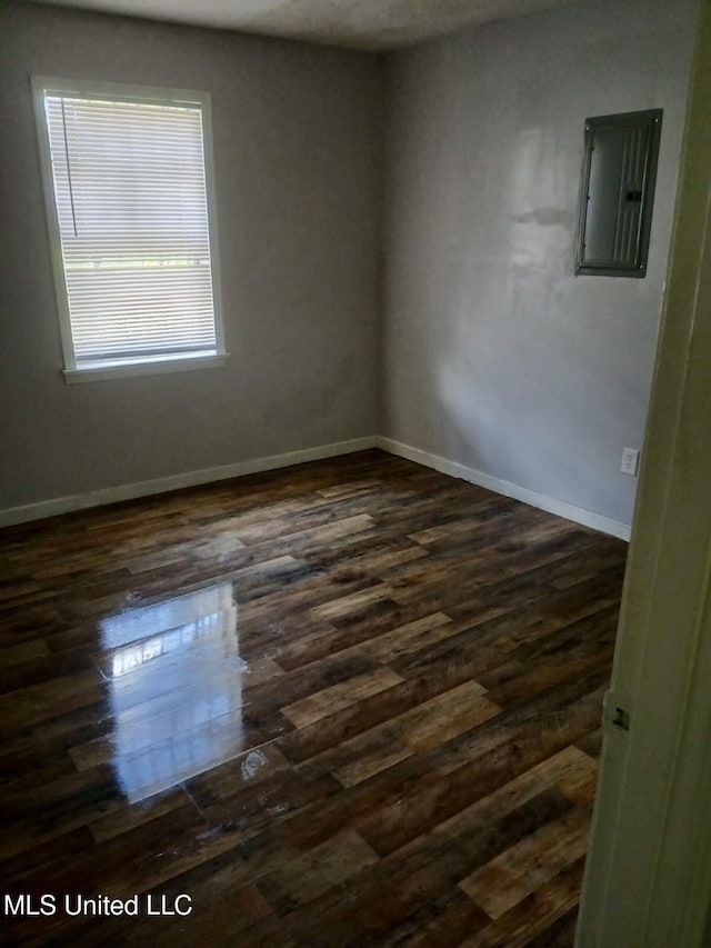 unfurnished room with electric panel, baseboards, and dark wood-style flooring