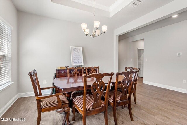 15380 Woodmanse Way, Diberville, MS 39540 - dining space with light wood finished floors, a chandelier, baseboards, a raised ceiling, and ornamental molding