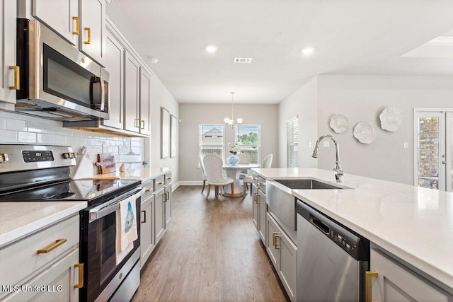 15380 Woodmanse Way, Diberville, MS 39540 - kitchen with stainless steel appliances, wood finished floors, gray cabinetry, a sink, and recessed lighting