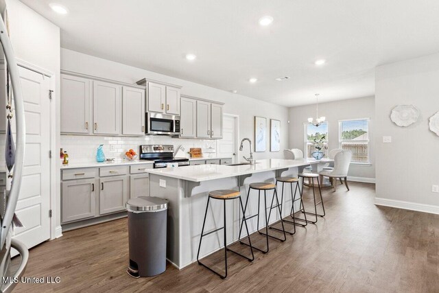 15380 Woodmanse Way, Diberville, MS 39540 - kitchen featuring stainless steel appliances, a kitchen bar, dark wood-style floors, an island with sink, and recessed lighting