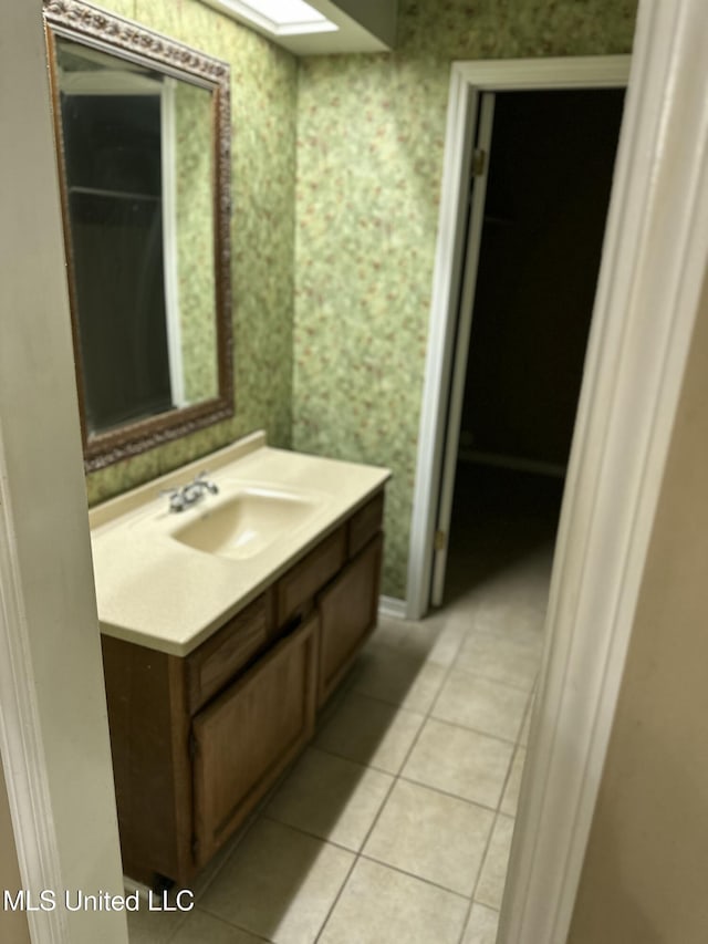 bathroom with tile patterned floors, a skylight, and vanity