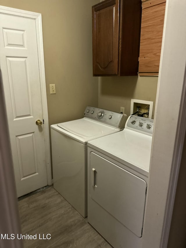 laundry area with cabinets, washer and dryer, and light hardwood / wood-style flooring