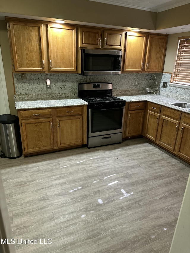 kitchen featuring tasteful backsplash, crown molding, light wood-type flooring, and appliances with stainless steel finishes