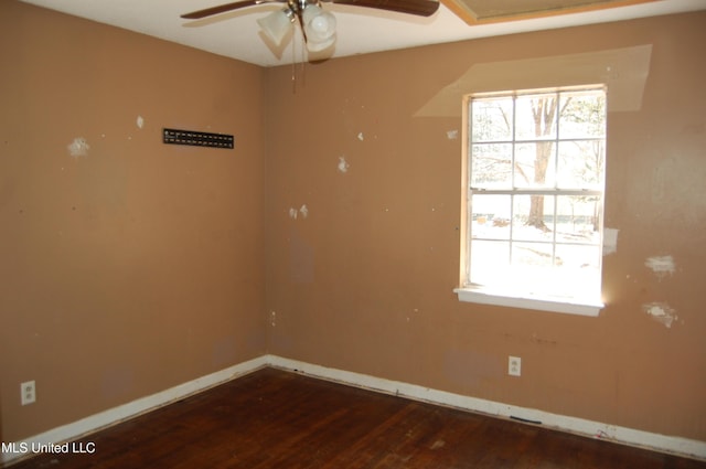 unfurnished room with dark wood-type flooring, plenty of natural light, a ceiling fan, and baseboards