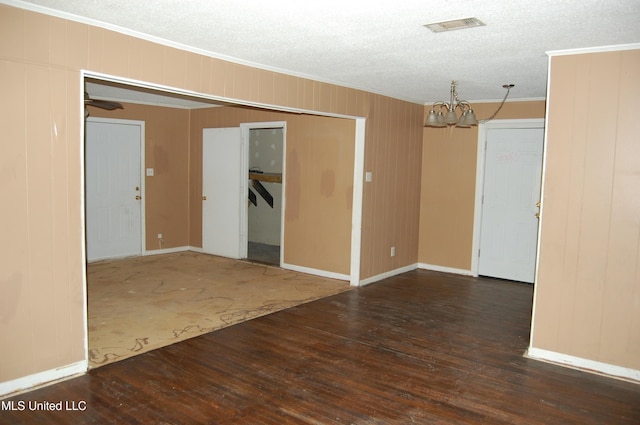 unfurnished room with visible vents, ornamental molding, a textured ceiling, wood finished floors, and a chandelier