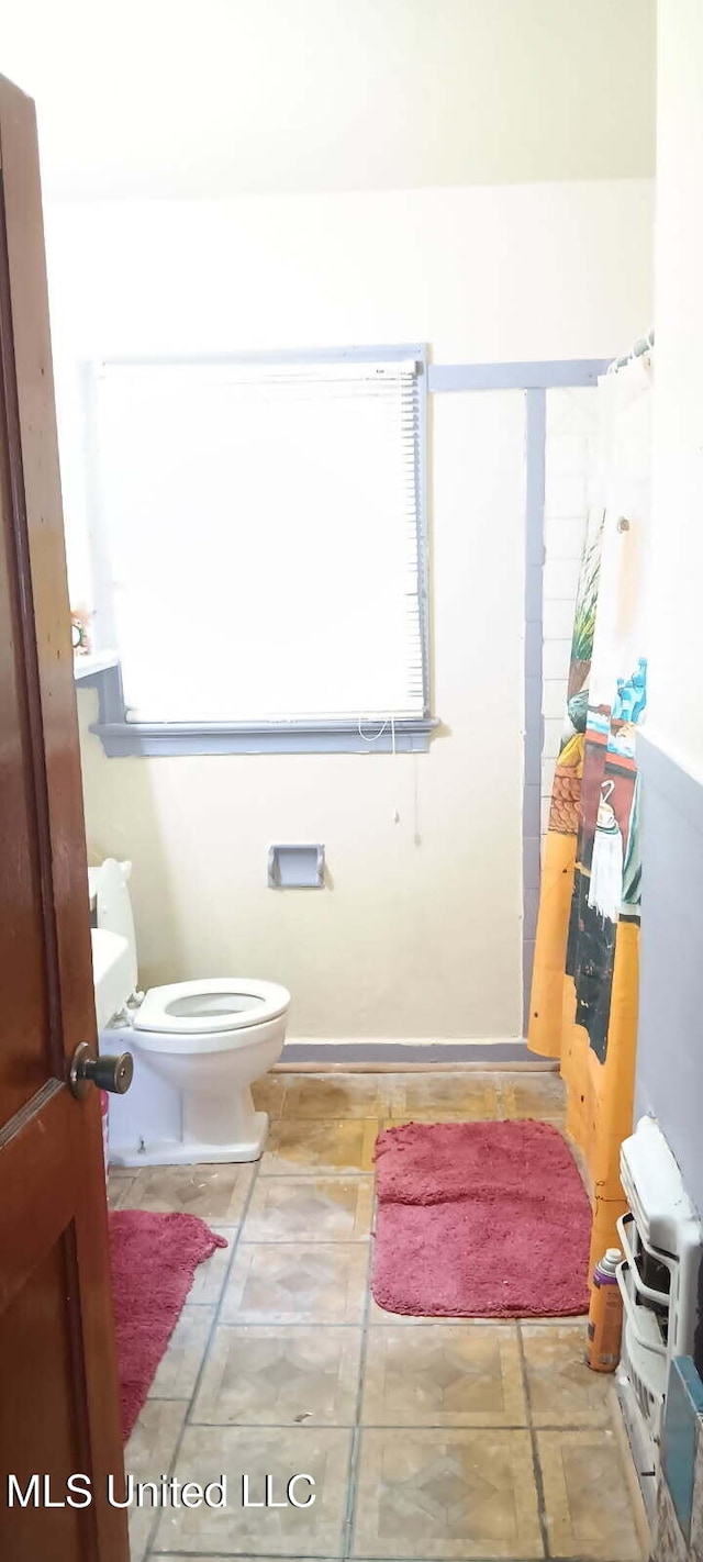 full bath with toilet and curtained shower