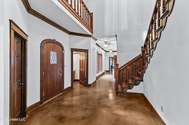 foyer entrance with ceiling fan, crown molding, and a towering ceiling