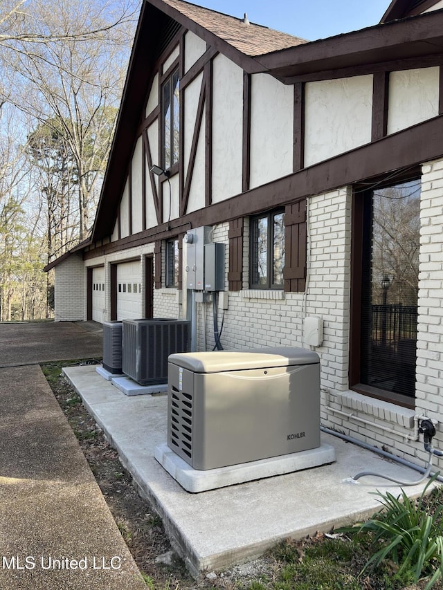 1609 SW Linda Dr, Clinton, MS 39056 - view of side of home with brick siding, central AC unit, stucco siding, and a garage