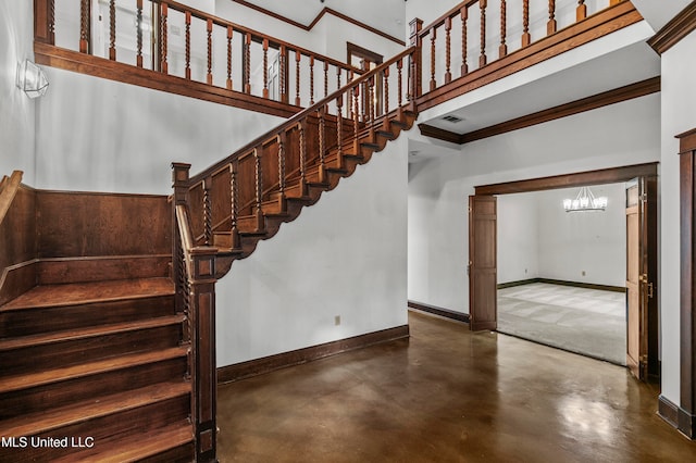 stairs featuring a chandelier, concrete flooring, crown molding, and a towering ceiling