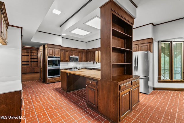 kitchen with appliances with stainless steel finishes, wooden counters, dark brown cabinets, and a kitchen island