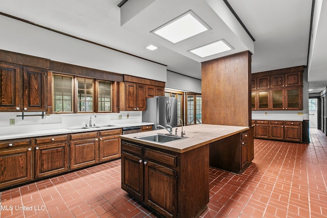 kitchen with appliances with stainless steel finishes, a healthy amount of sunlight, sink, and a center island with sink