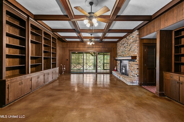 unfurnished living room with wood walls, coffered ceiling, beamed ceiling, a fireplace, and ceiling fan