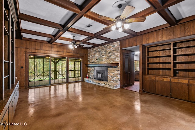 unfurnished living room with beam ceiling, ceiling fan, concrete flooring, wooden walls, and coffered ceiling