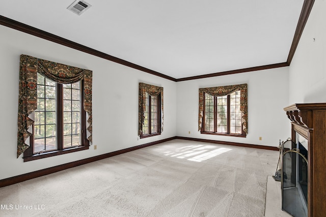 unfurnished living room with a wealth of natural light, ornamental molding, and light colored carpet