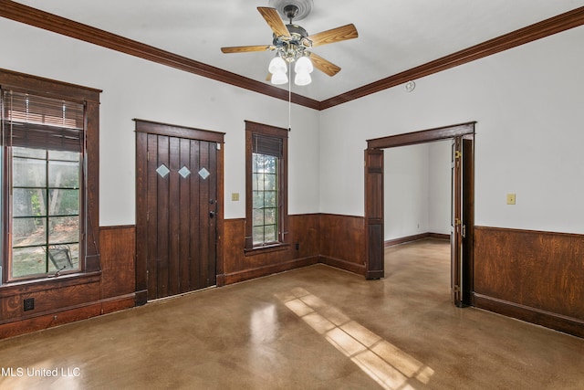 entrance foyer with ornamental molding, wood walls, concrete flooring, and ceiling fan