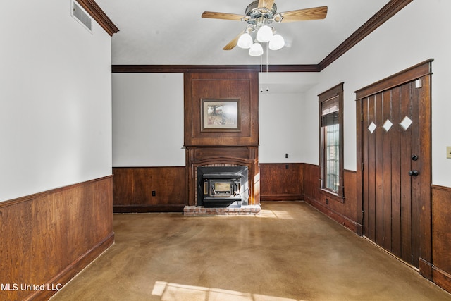 unfurnished living room featuring wooden walls, crown molding, a wood stove, and ceiling fan