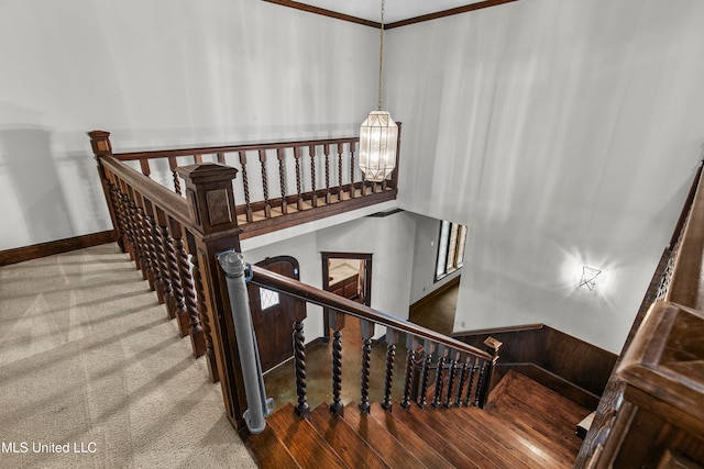 stairway featuring a notable chandelier, ornamental molding, hardwood / wood-style flooring, and a high ceiling