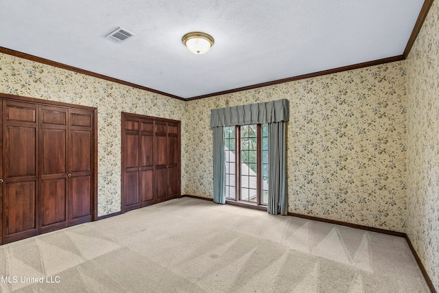 unfurnished bedroom with light carpet, ornamental molding, and a textured ceiling