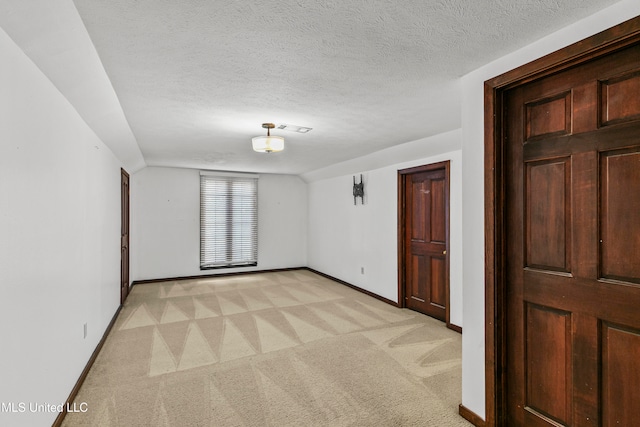 unfurnished room featuring a textured ceiling and light colored carpet