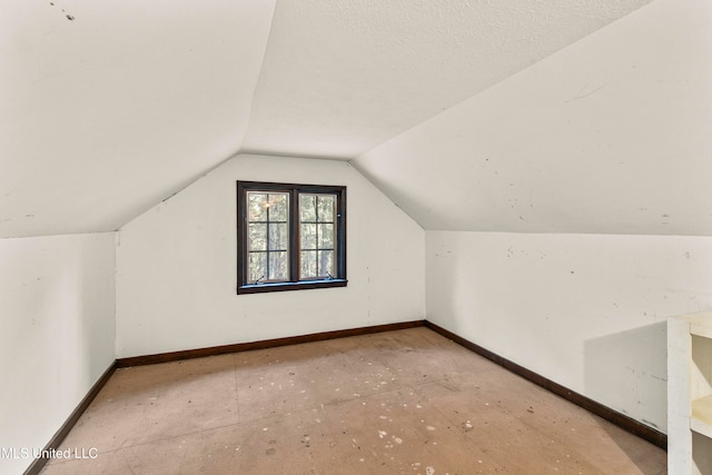 additional living space with a textured ceiling and vaulted ceiling