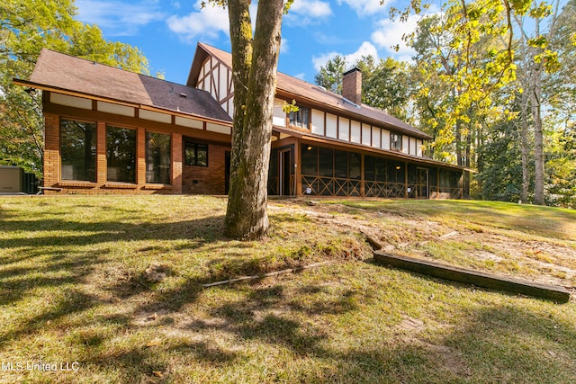 rear view of property with a yard and a sunroom