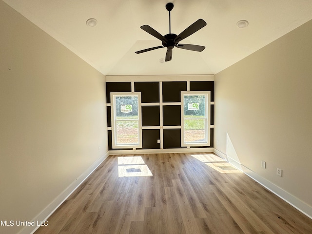 empty room featuring light hardwood / wood-style flooring, vaulted ceiling, and plenty of natural light