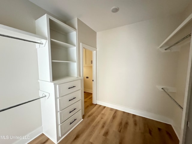 walk in closet with light hardwood / wood-style flooring