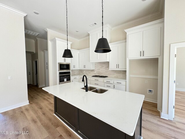 kitchen featuring a center island with sink, white cabinetry, sink, and appliances with stainless steel finishes