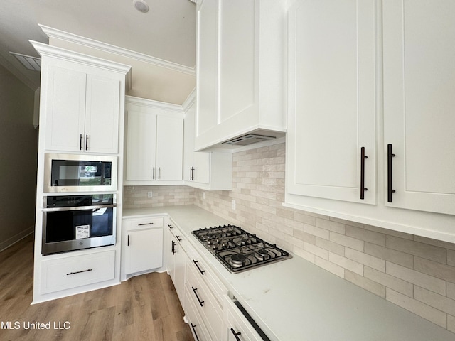 kitchen with white cabinetry, stainless steel appliances, tasteful backsplash, light hardwood / wood-style floors, and custom range hood