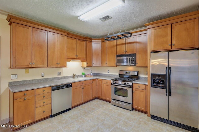242 Commonwealth Ave, Brandon, MS 39047 - kitchen with appliances with stainless steel finishes, a textured ceiling, light countertops, brown cabinets, and light tile patterned flooring
