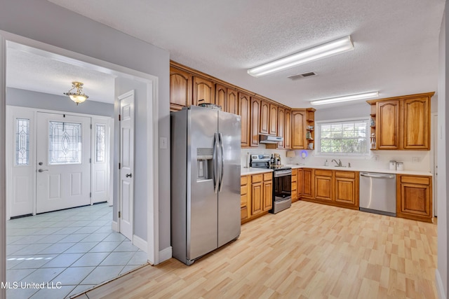 kitchen featuring a sink, open shelves, appliances with stainless steel finishes, under cabinet range hood, and visible vents
