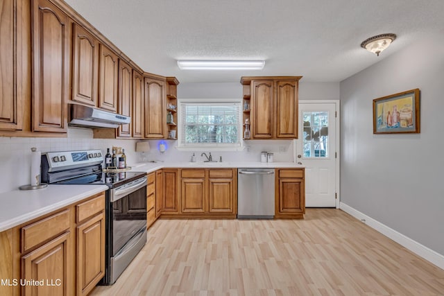 kitchen with open shelves, appliances with stainless steel finishes, brown cabinetry, under cabinet range hood, and light wood-style floors