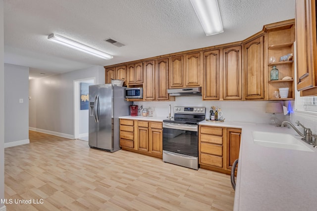 kitchen featuring light countertops, a sink, appliances with stainless steel finishes, under cabinet range hood, and visible vents