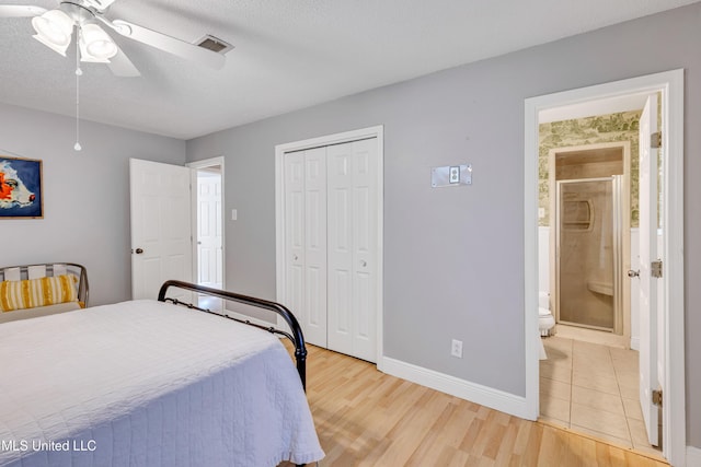 bedroom with a closet, a textured ceiling, visible vents, baseboards, and light wood-type flooring